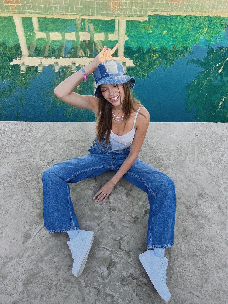 Josephine Skriver wears denim dungaree, corset top, and denim bucket hat at Coachella